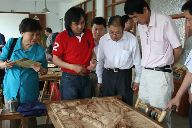 黃小明給中國(guó)工藝美術(shù)學(xué)會(huì)秘書(shū)長(zhǎng)王山、中國(guó)美術(shù)學(xué)會(huì)副理事長(zhǎng)唐克美等領(lǐng)導(dǎo)介紹作品《晨》的雕刻技法